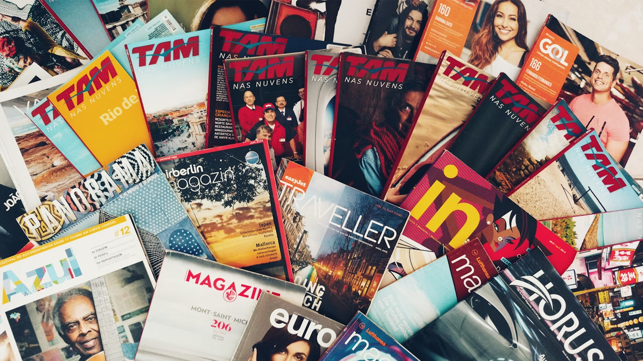 Stack of old magazines, curled edges, faded covers, various colors, placed on a wooden surface