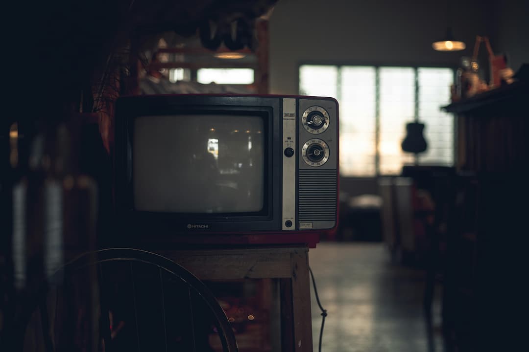 Vintage Hitachi television with dials, placed on a wooden stand in a dimly lit room