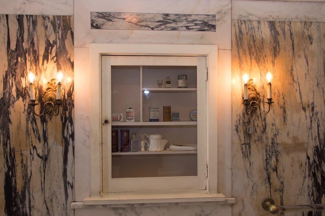 Vintage bathroom cabinet with glass door, surrounded by marble walls