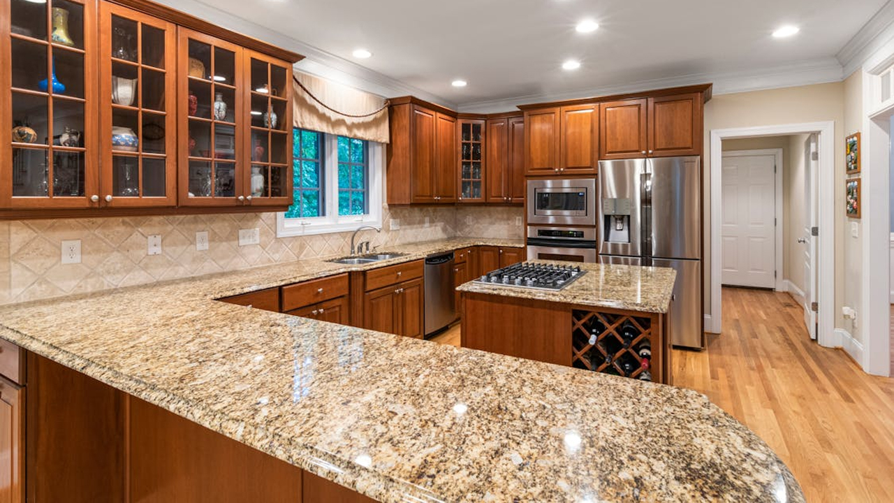 granite kitchen countertop, stainless steel sink, wooden cabinets, tiled backsplash, built-in stove, overhead lighting, modern kitchen design