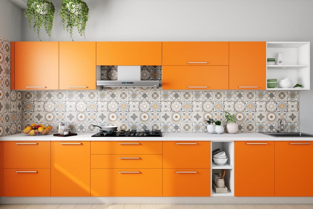 modern kitchen, bright orange cabinets, patterned tile backsplash, white countertop, gas stove with pot, fruit basket, potted plants, open shelves with dishes, hanging green plants