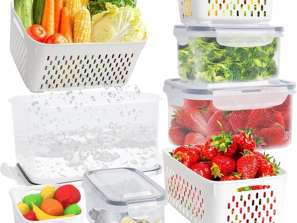 assorted fruit and vegetable storage containers, white plastic bins and clear lidded boxes, filled with produce like strawberries, broccoli, carrots, grapes, and leafy greens