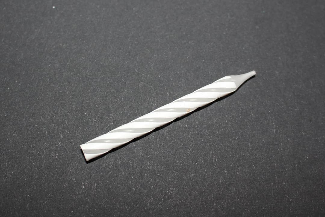 White spiral birthday candle lying horizontally on a black background