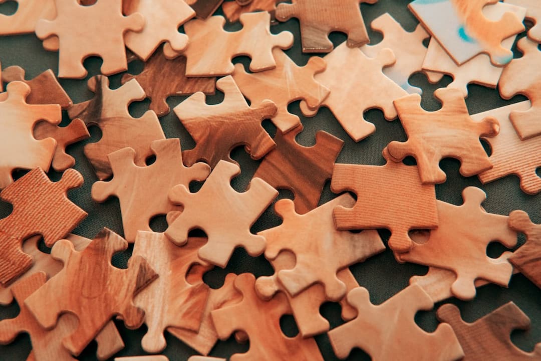Scattered brown-toned jigsaw puzzle pieces on a dark surface