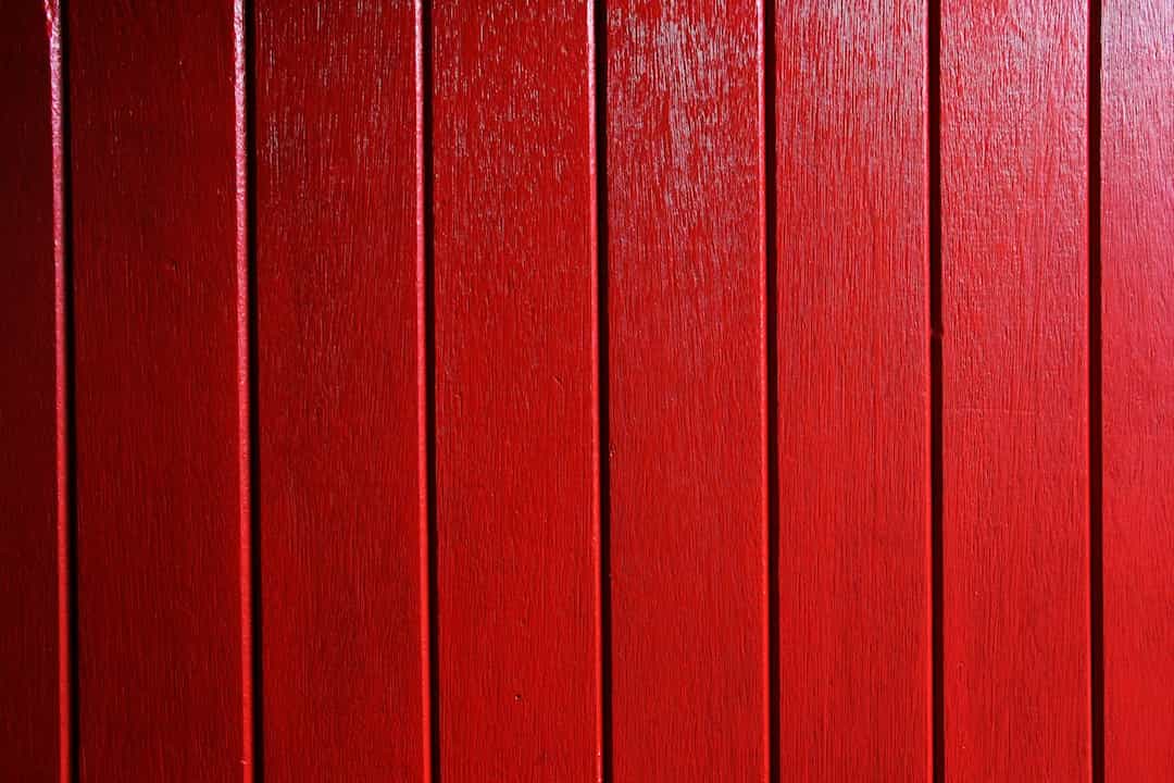 Vertical red wooden panels, evenly spaced grooves, bright glossy finish, natural wood texture visible beneath paint