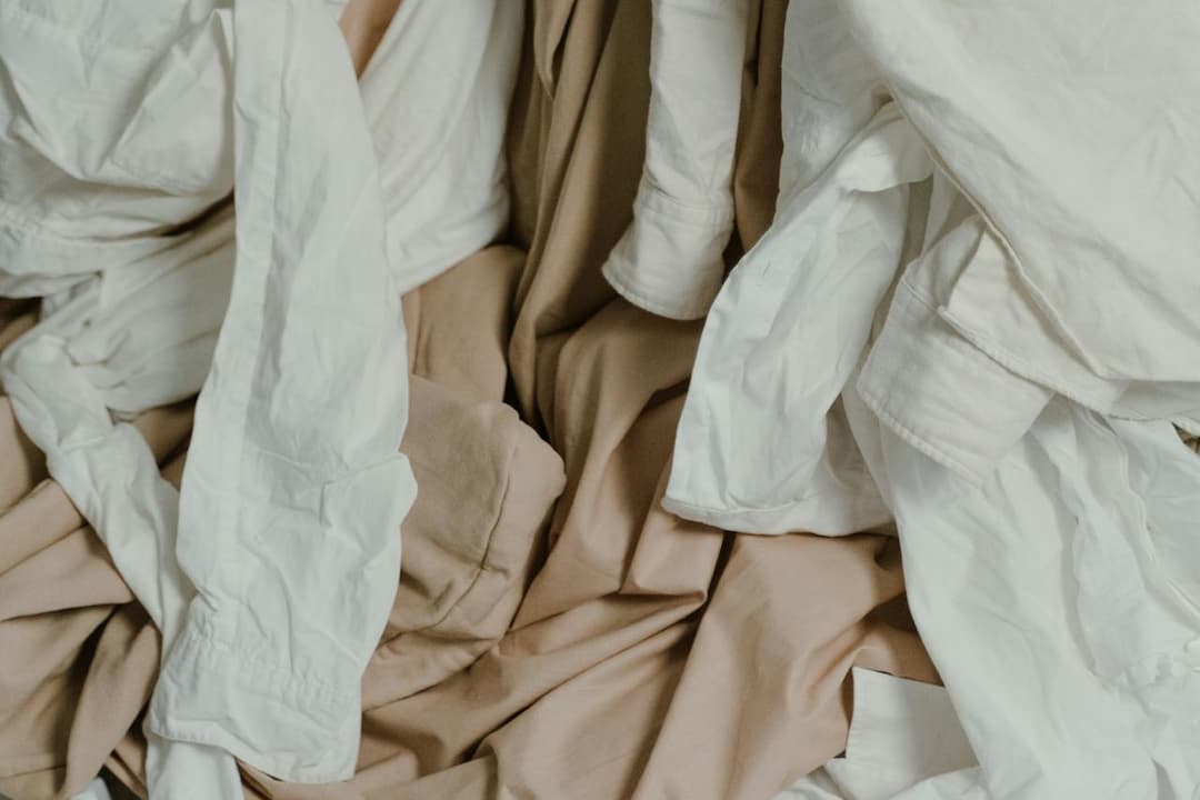 Wrinkled white and beige clothing piled together, showing a mix of shirts and fabric textures