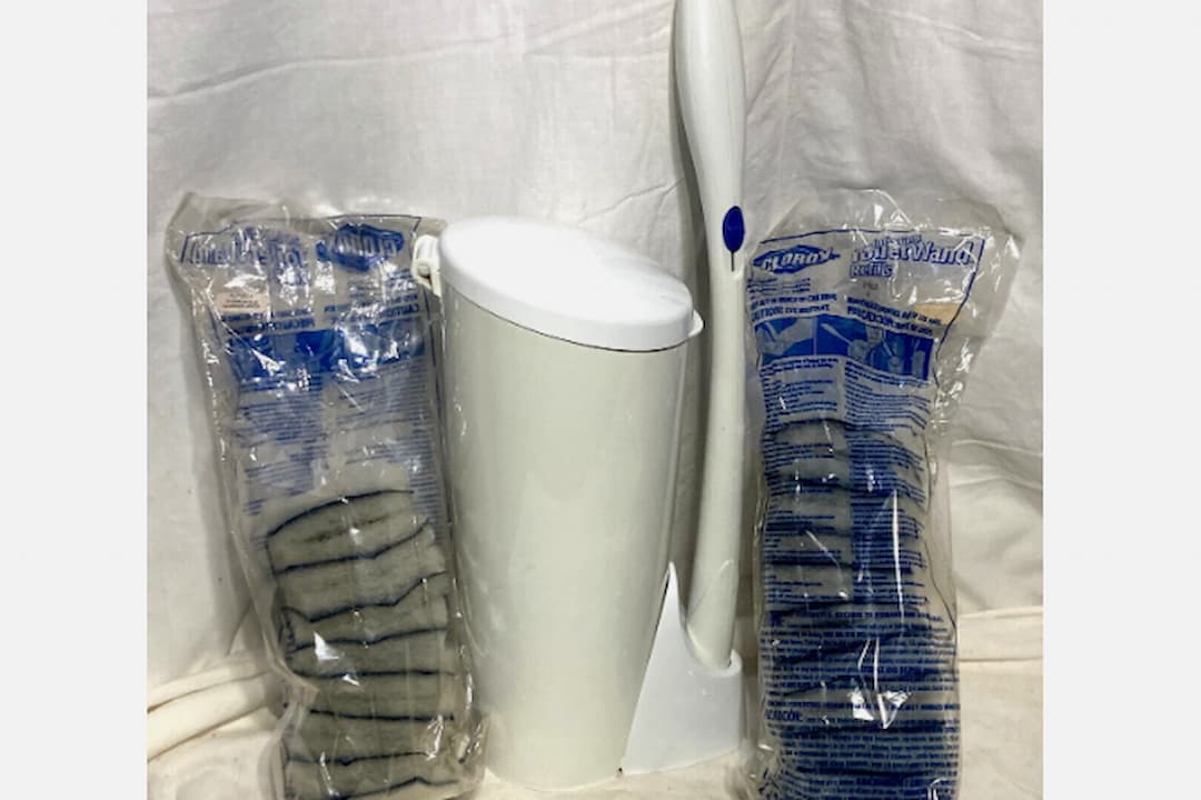 Toilet wand cleaning system with white holder, long white handle with blue button, two refill packs containing disposable scrub pads in plastic packaging