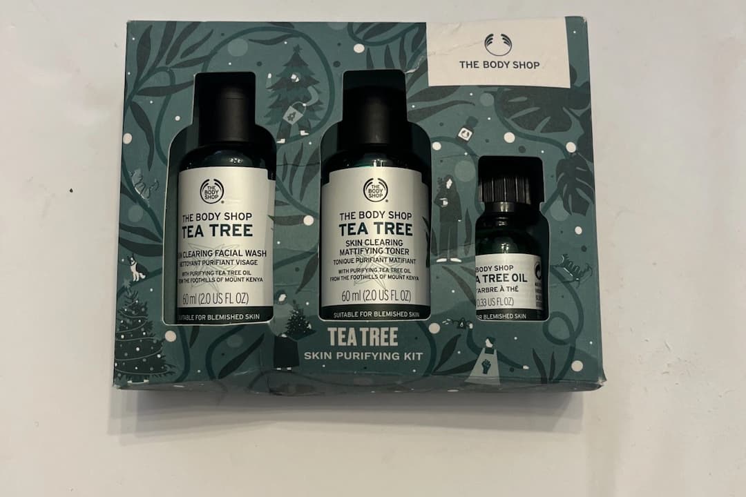 The Body Shop Tea Tree Skin Purifying Kit, includes facial wash, mattifying toner, and tea tree oil in a green festive-themed box