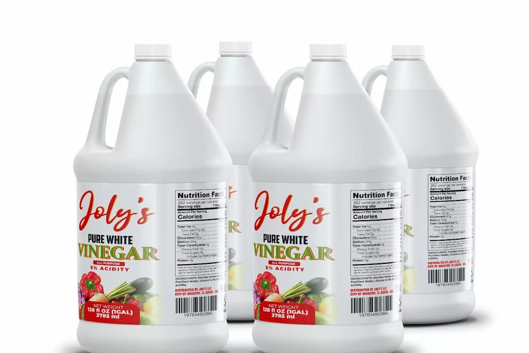 Four large white plastic gallon bottles of Joly’s Pure White Vinegar, 5% acidity, labeled with colorful text and fruit imagery