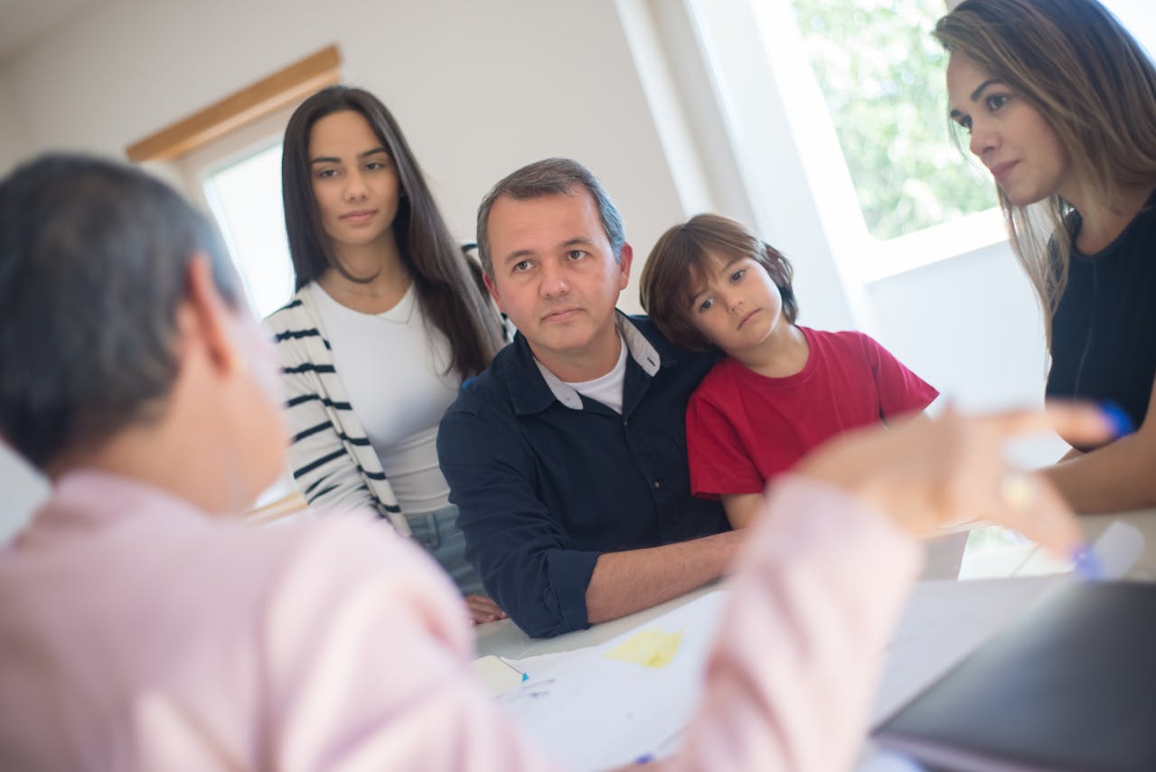 Family of four attentively listening to a professional across the table during a meeting