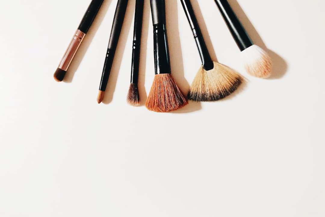 Set of six makeup brushes with black handles arranged in a fan shape on a white surface