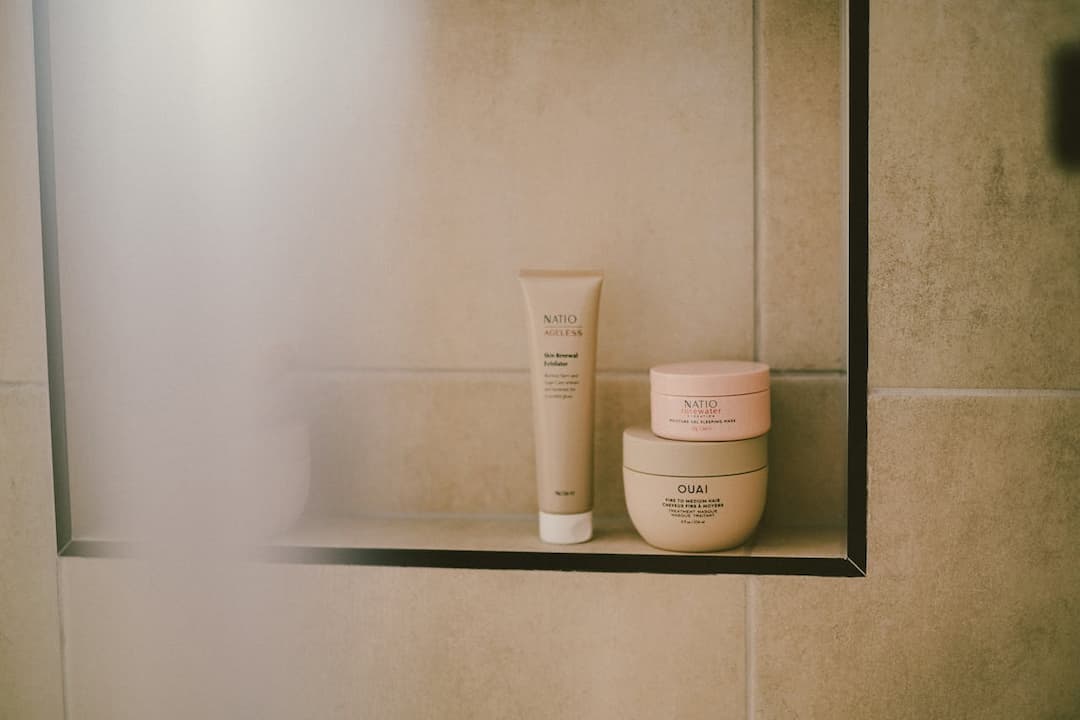 Natio and Ouai skincare products arranged neatly on a tiled bathroom shelf